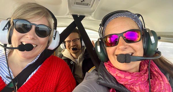 Das junge Paar feiert seine Verlobung mit einem Rundflug über Amrum. Beide haben Kopfhörer auf und freuen sich den Leuchtturm aus der Luft zu sehen
